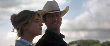 A still from Twisters of Glen Powell, who plays Tyler Owens, wearing a cowboy hat looking at Daisy Edgar-Jones, who plays Kate Carte