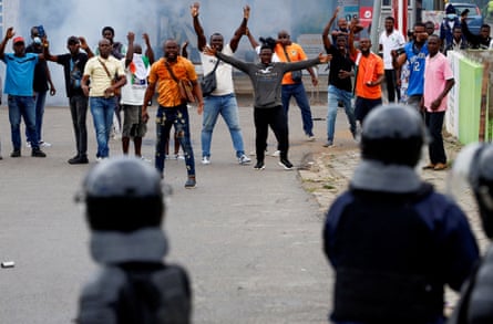 Demonstrators gesture at riot police