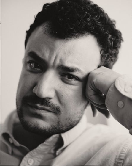 A man furrows his brow and poses with his hand on his temple