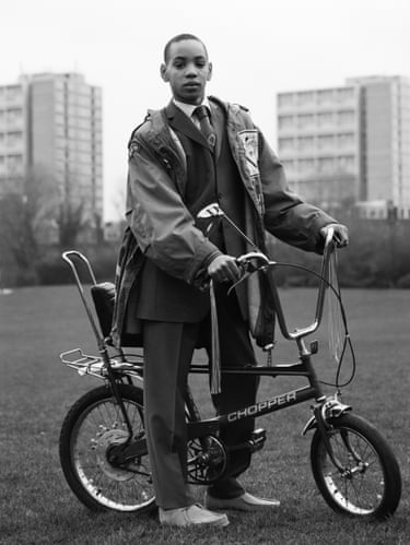 Teenage boy on a chopper bike in a park surrounded by tower blocks
