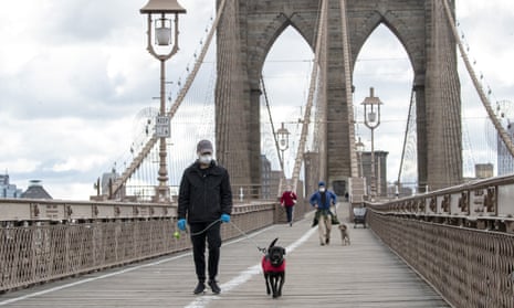 People wear facial masks for protection as they walk their dogs on the Brooklyn Bridge in New York on Friday.