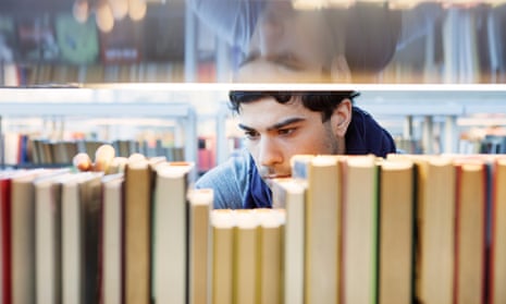 Serious young man choosing book in library