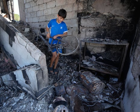 A Lebanese boy lifts his damaged bicycle from rubble in his destroyed home
