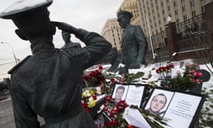 Photographs of slain pilot Oleg Peshkov, left, and rescuer Alexander Pozynich are placed at a monument to Soviet Officers in Moscow