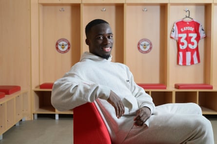 Michael Kayode poses with a Brentford shirt in the background.