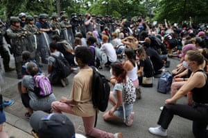 Demonstrators take a knee in front of law enforcement officers during a protest against the death of George Floyd, near the White House on 3 June.