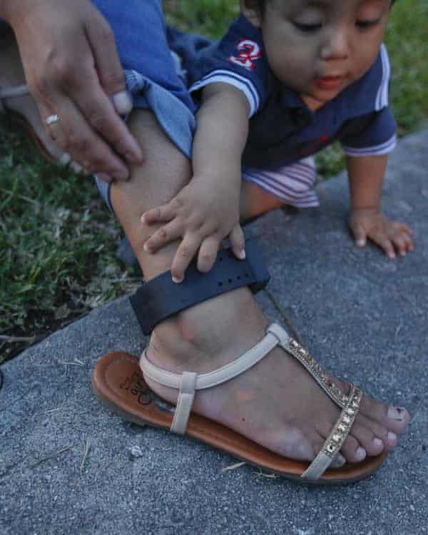 baby boy reaches for mother’s ankle monitor