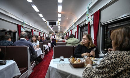 The dining carriage of the Doğu Express train filled with passengers at night.