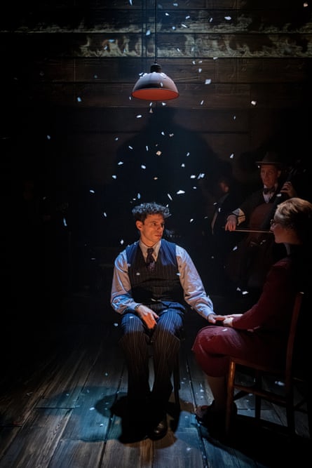 Krikler illuminated against darkness and what looks like tickertape falling on him, his mother in shadow