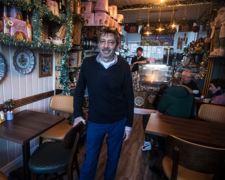 Tony Musumeci standing for the photographer beside diners in his deli