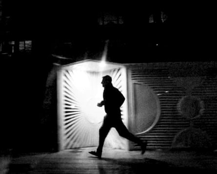 Silhouette of a running man at night in a street in Iran during protests.