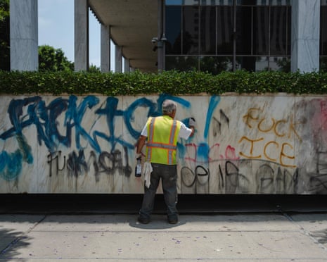 A man cleans ‘Fuck Ice’ graffiti off the Robert Young Federal Building on 9 June.
