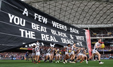 Para pemain Magpies berlari melewati spanduk mereka sebelum pertandingan di Adelaide Oval.