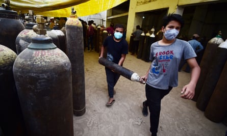 People carry a medical oxygen cylinder at a refilling station in Allahabad.