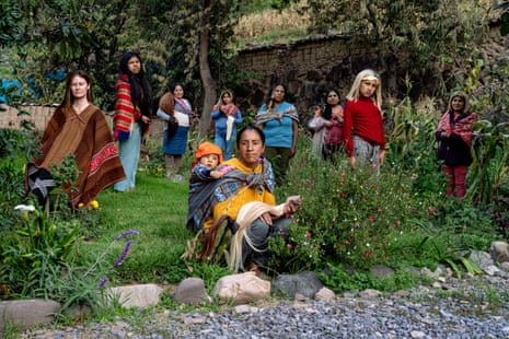 A group of women in traditional woven shawls pose in a garden