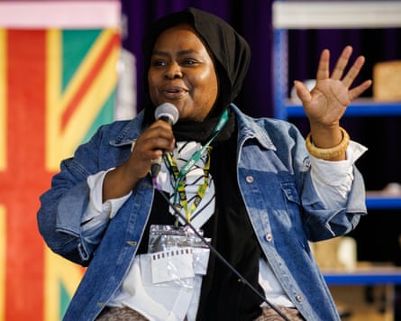 Writer Muneera Pilgrim speaks into a microphone, raising her hand while taking questions.