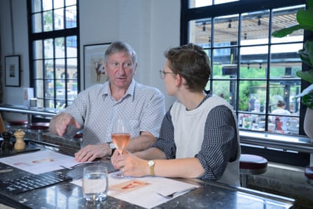 A man and woman facing each other, side by side at a restaurant table