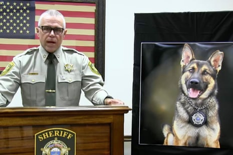 a sheriff speaks next to a photograph of a dog