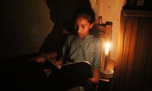 A girl reads a book by candlelight during a blackout in Colombo, Sri Lanka