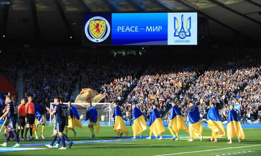 The Ukraine players walk onto the pitch each draped in their national flag.