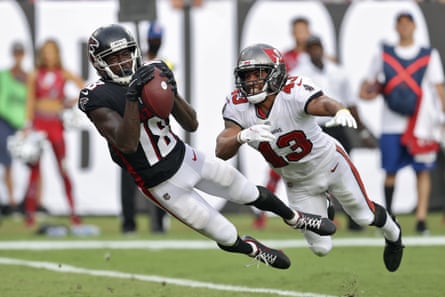 football player catches ball while another player dives near him