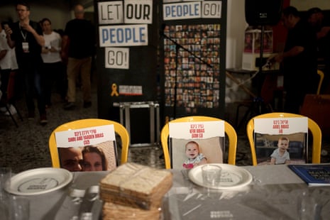 Three yellow plastic chairs have photographs attached to them of the Bibas family, who are hostages held in Gaza. The chairs are behind a Passover Seder table set on Thursday, at the communal dining hall at kibbutz Nir Oz in southern Israel.