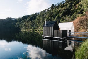 Small project architecture awardFloating sauna, Derby, Tasmania. By Licht Architecture. Two gable sheds – one a changing room, the other a sauna – sit on a lake against the backdrop of quarry cliffs and rainforest. A small pedestrian bridge connects the pontoon to the shore.