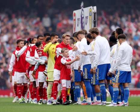 Players of Arsenal and Leeds United shake hands on the pitch prior to their Premier League match.