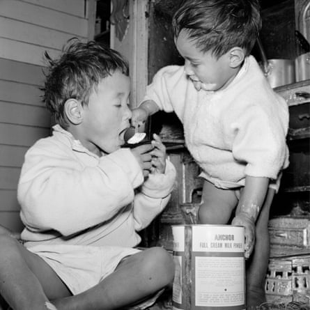Two boys share a spoonful of canned milk