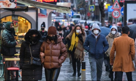 People wearing face masks walk on a street in Istanbul Turkey.
