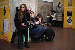 Girls hold their mobile phones as they take refuge in a metro station in Kyiv