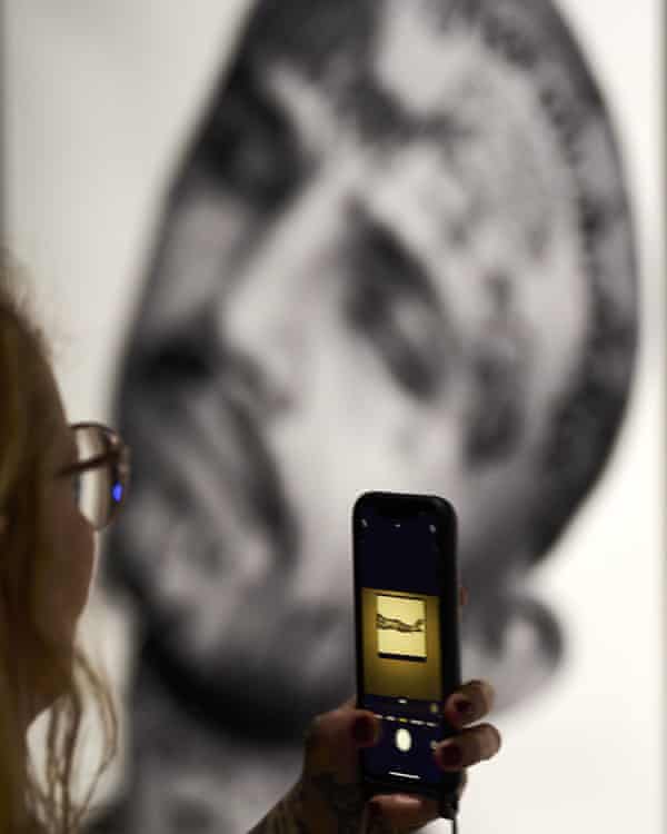 A woman takes a photo of a man with facial tattoos at the exhibition.