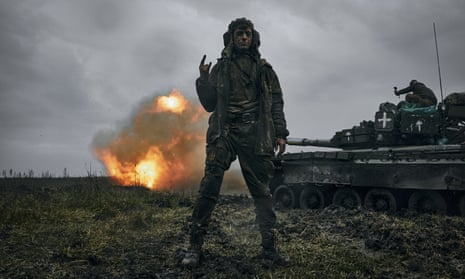 A Ukrainian soldier gestures as a captured Russian tank T-80 fires at the Russian position in Donetsk region, Ukraine.