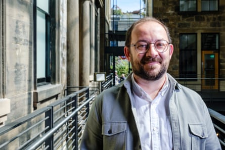 A man standing on a walkway outside a stone building