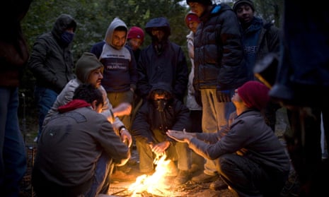 Migrants warm themselves by a campfire at their camp in the Grande-Synthe woods near Calais.