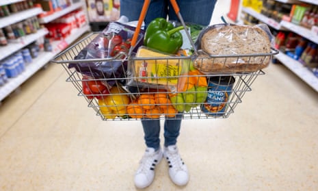 A woman holds a basket of goods in a supermarket