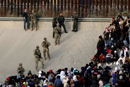 Migrants congregate on the banks of the Rio Grande at the US border with Mexico, on 20 December 2022, where members of the Texas national guard cordoned off a gap in the border wall.