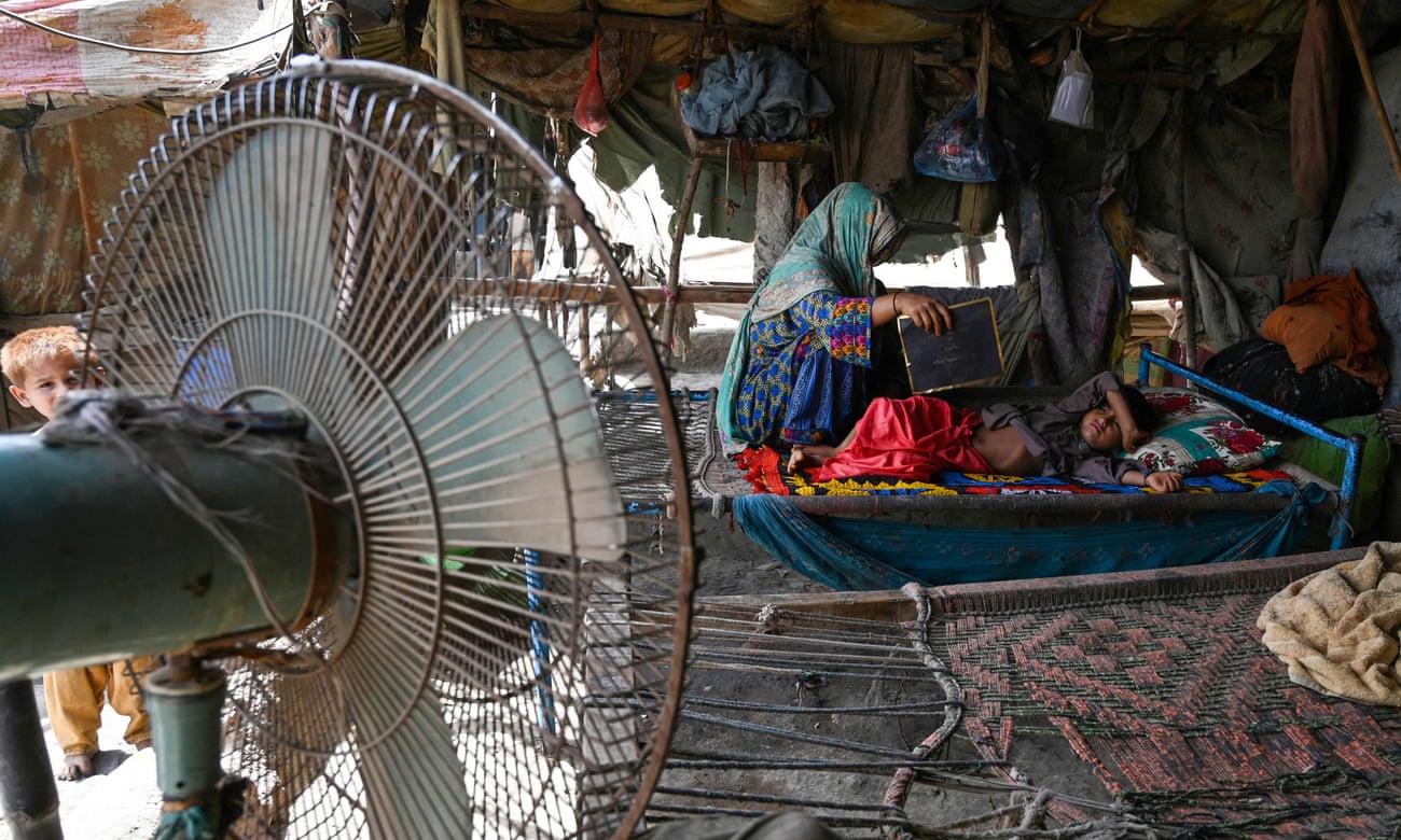A woman uses a paper sheet to fan her child amid a power cut during a heatwave in Jacobabad