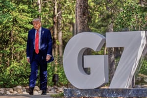 Donald Trump walks past a G7 sign