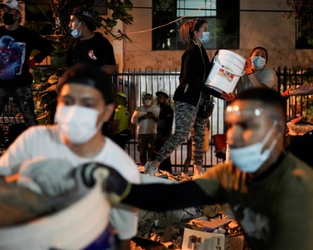 People wearing masks pass buckets to each other as they attempt to clear the site