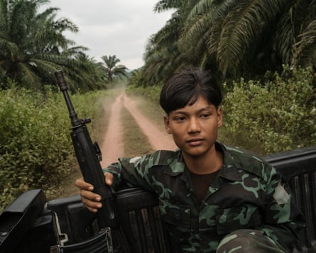A rebel soldier rides in the back of a pickup truck holding a gun