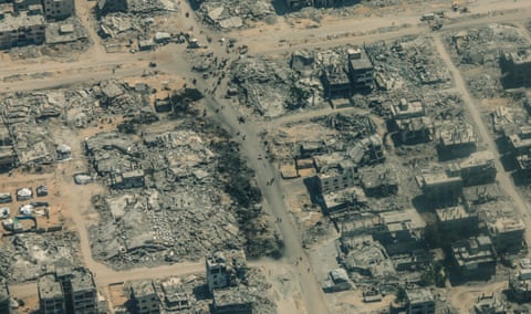 میتوان مردم را دید که دور خرابههای یک محله در مرکز نوار غزه جمع شدهاند.