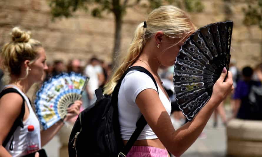 Two women use fans to fight the scorching heat during a heatwave in Seville on 13 June 2022.