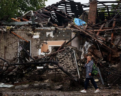 A woman walks in front of a house destroyed in a Russian strike on a residential neighbourhood in Kyiv