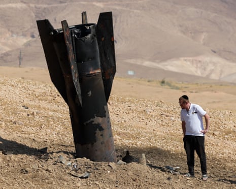 A man checks a fallen rocket half-buried in the ground on the outskirts of Jericho on Monday.