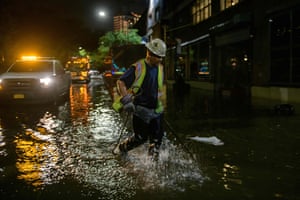 A worker unblocks drains on a street affected by flood water in Brooklyn