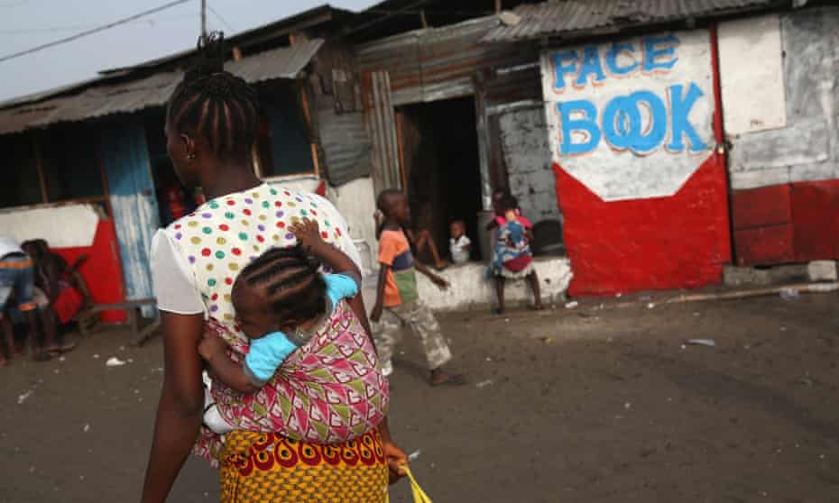 A woman and her child pass by an internet cafe in the West Point slum in Monrovia, the Liberian capital