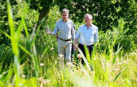 Miliband and Reed talking as they walk through long grass