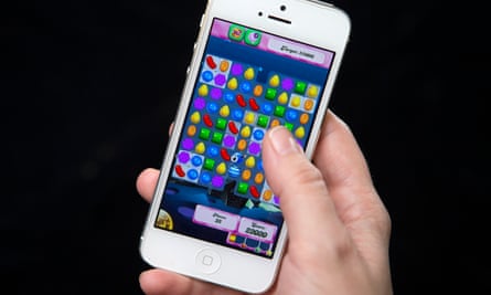 The hand of a person playing Candy Crush Saga on a smartphone.