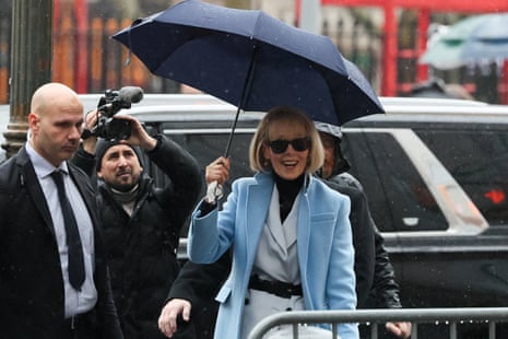 a woman with a blue coat, black sunglasses and an umbrella